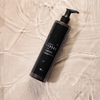 IdHAIR Niophlex Rebond Shampoo bottle with water droplets on rippled surface – vegan bond-building shampoo for damaged hair